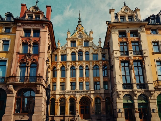 Auf dem Bild sind beeindruckende Beispiele der Jugendstil-Architektur in Riga zu sehen. Die bunten Fassaden der Gebäude zeigen kunstvolle Verzierungen und charakteristische Elemente dieses Baustils. Abgerundete Formen, florale Motive und detaillierte Ornamentik prägen das Stadtbild. Besonders auffällig sind die dekorativen Balkone und die eleganten Fensterrahmen. Diese Pracht spiegelt die kreative Energie und den Reichtum der Epoche wider und lädt zu einem faszinierenden Spaziergang durch Rigas historische Viertel ein.